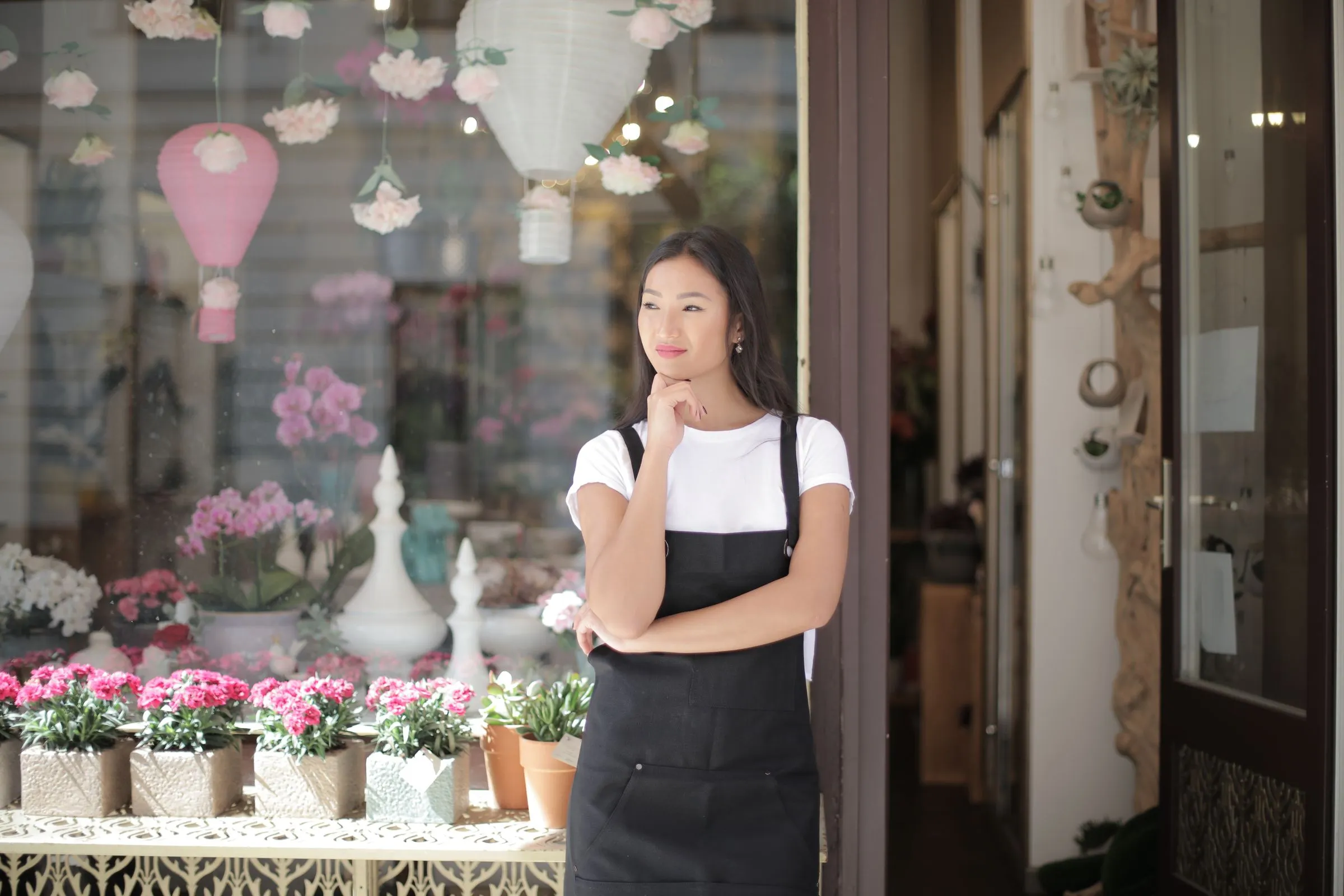Fleuriste debout devant la vitrine de sa boutique