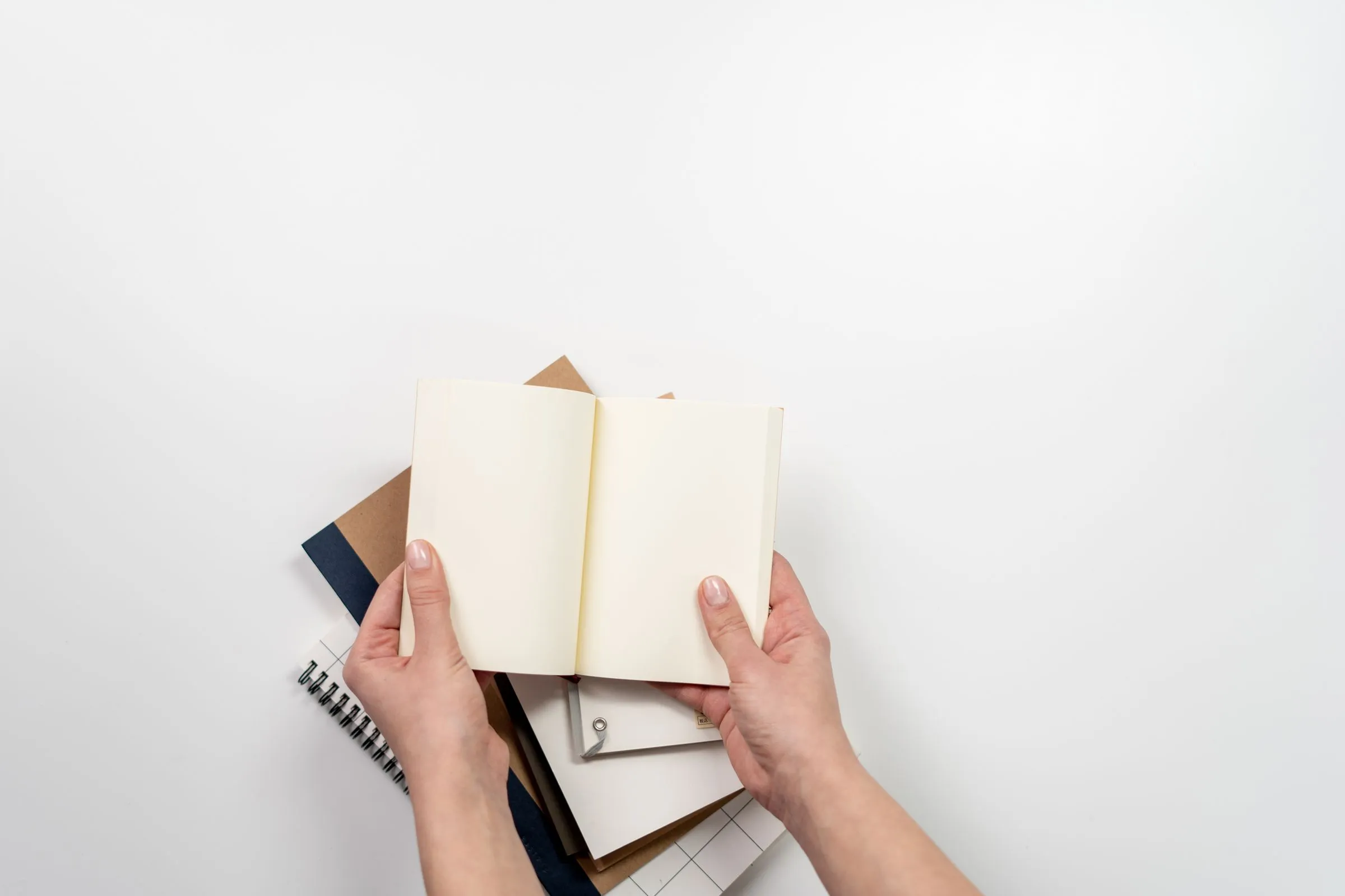 Mains qui tiennent des carnets ouverts sur fond blanc